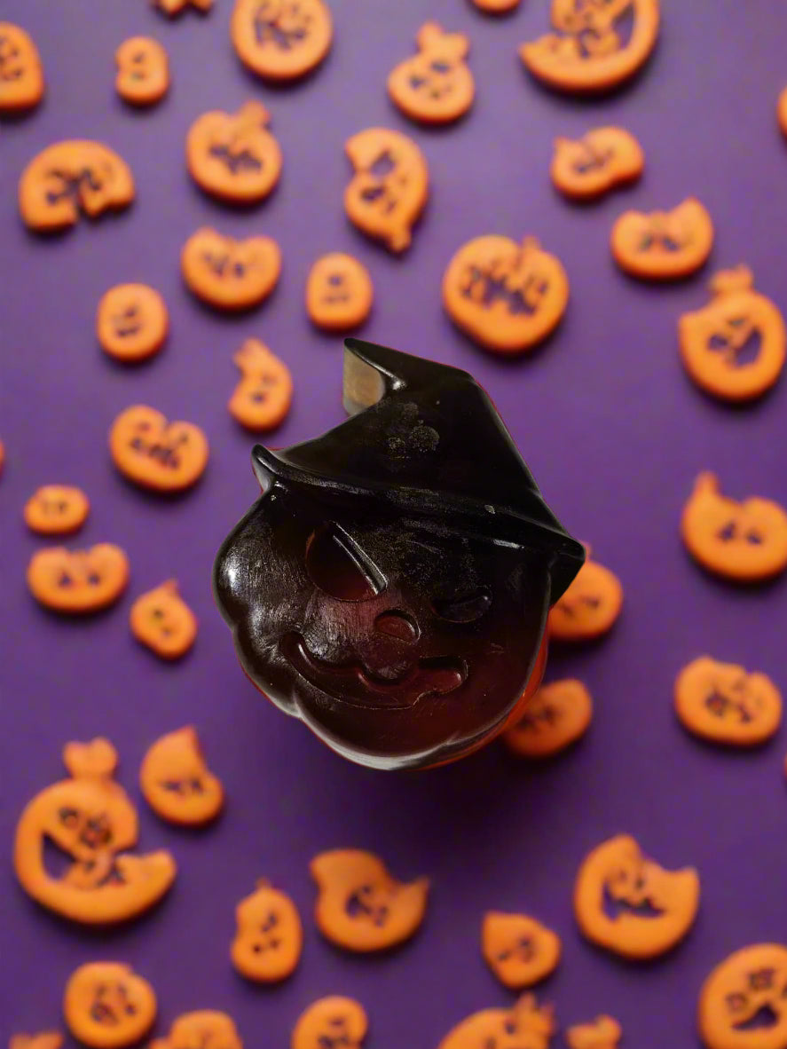 pumpkin wearing a witches hat shaped soap on a Halloween style background