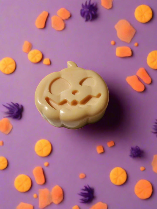Orange pumpkin shaped soap on a Halloween themed background background
