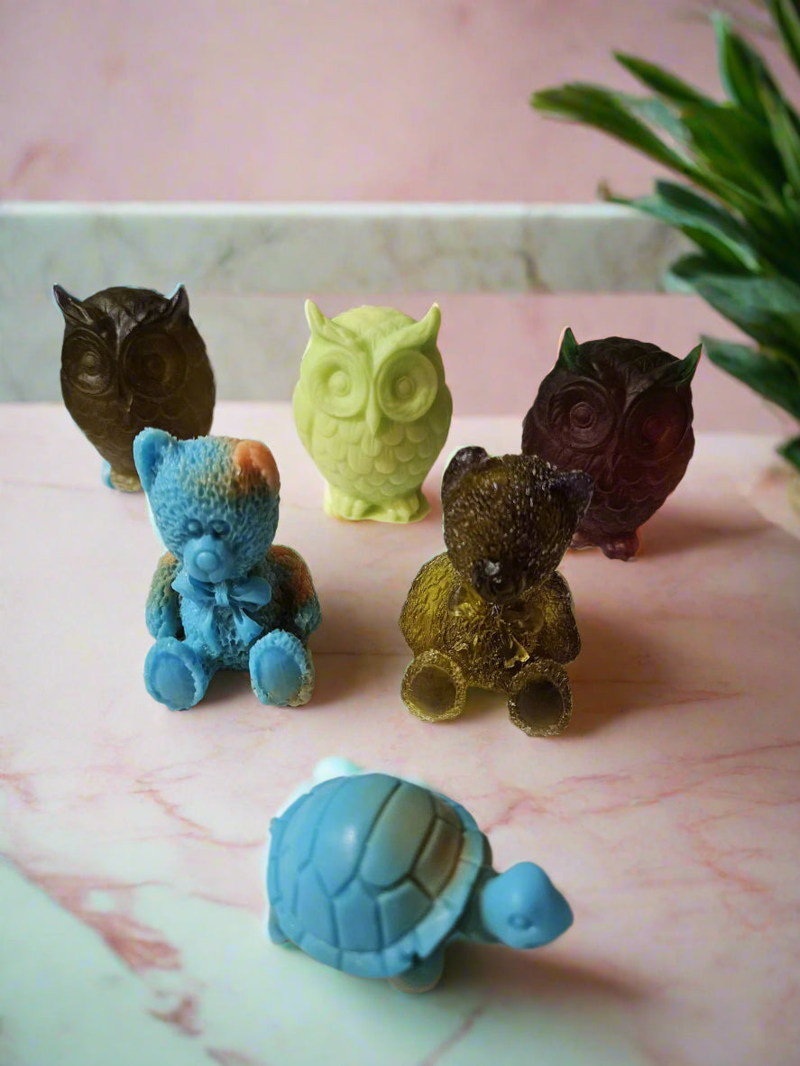 Colorful animal-shaped soap bars on a white surface with a neutral background