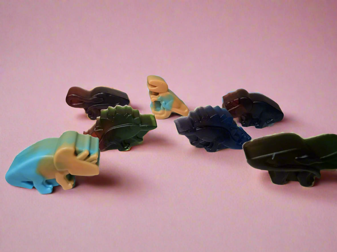 Set of colorful dinosaur-shaped soap on a pink background